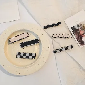 Detail view of various acrylic checkerboard and solid color seamless hair clips on a plate