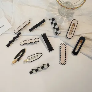 Detailed flat lay of acrylic checkerboard and solid hair clips on white fabric