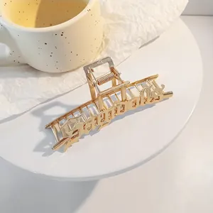 Primer plano de una pinza de pelo de metal dorado con diseño de letras Goddess