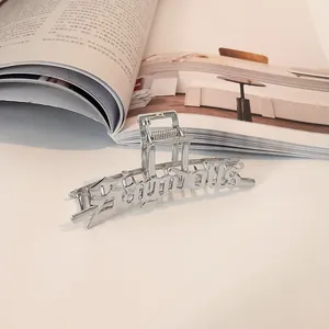 Detalle de pinza para el pelo plateada con letras góticas caladas estilo Angels
