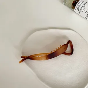 Detailed view of an amber matte banana clip with inner teeth on a white ceramic tray