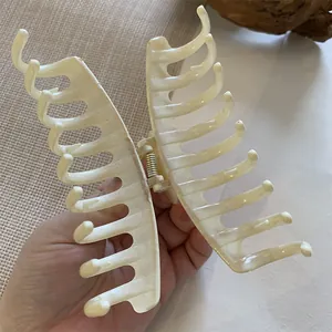Detalle de una pinza de pelo grande color crema mate con un fuerte resorte de metal dorado