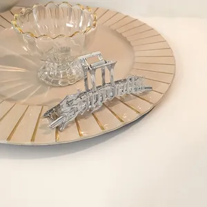 Pinza para el pelo de metal plateado con diseño gótico en un plato de cerámica crema
