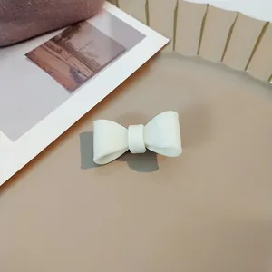 Elegant cream-colored acrylic bow hair clip with a smooth glossy finish for women