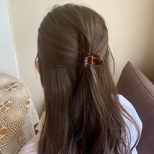 Close-up of a large amber acrylic hair claw clip used in a woman's hair bun