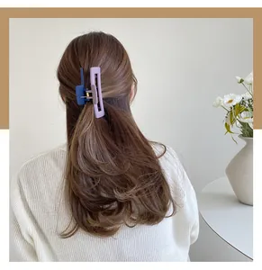 Detail view of purple and navy blue matte acrylic rectangle hair claws on long hair