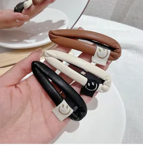 Close-up of PU leather teardrop hair clips in brown, beige, and black with smiley faces