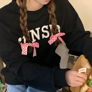 Détail de chouchous à nœuds à carreaux roses et blancs portés sur une tresse