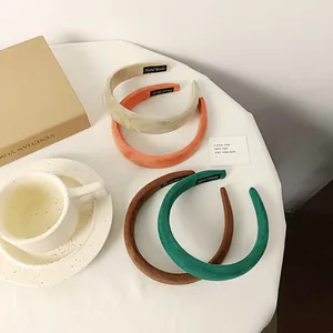 Detalle de diademas de terciopelo de colores con etiqueta artesanal en una mesa