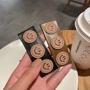 Detail view of rectangular PU leather hair clips with three cute smiley face patches