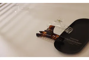 Close-up of elegant amber tortoise shell and clear acrylic hair clips on a black tray