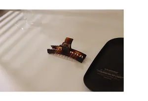 Detailed close-up of a brown tortoiseshell hair claw clip with a resin glossy finish