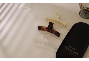 Three large acrylic hair claws in cream, tortoiseshell, and transparent finish on a tray