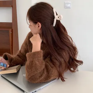 Elegant white plush hair claw clip for women shown in a cozy home setting with model