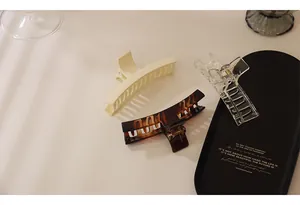 Detailed view of three large acrylic hair claws in cream, tortoiseshell, and clear finishes