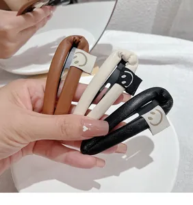 Detailed close-up of three PU leather tear-drop hair clips in black, brown and beige colors