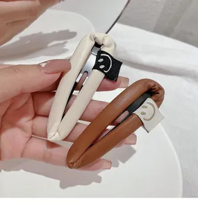 Detail of drop-shaped PU leather BB hair clips with cute woven smiley face tags