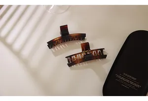 Detail of two amber tortoise shell hair claws on a black tray with elegant light shadows