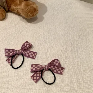 Gros plan de chouchous à nœuds à carreaux violets sur un fond en tissu doux et texturé