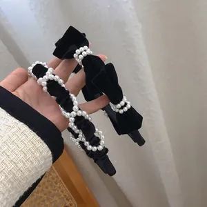 Elegant black velvet headband with vintage bow and pearls for a retro chic look