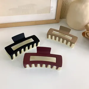 Three-color square acrylic matte hair claws in black, wine red, and khaki on a beige table