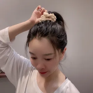 Plush cream scrunchie with cute bear tag on a high ponytail for winter hair styling