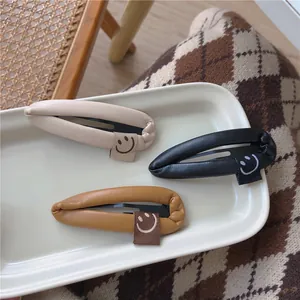 Three leather wrapped teardrop hair clips with smile tags on white ceramic plate