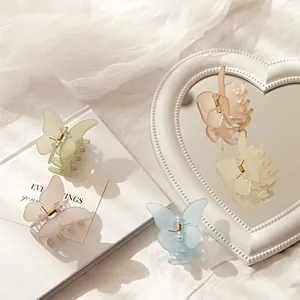 Detalle de pinzas de mariposa translúcidas en tonos pastel sobre una tela blanca suave