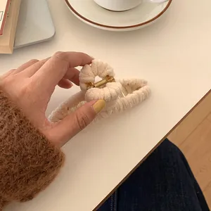 Close-up of a large cream plush hair claw clip with a soft texture and metal spring
