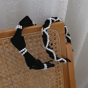 French vintage black velvet headbands set with elegant pearls and bows on a retro chair