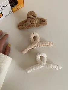 Detailed view of three plush velvet hair claws in brown, beige, and white colors