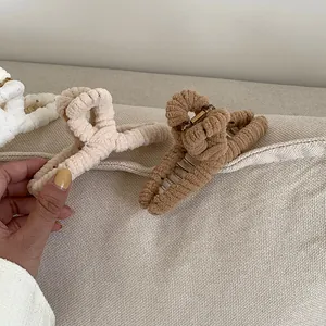 Detail of plush corduroy hair claws in white, beige, and brown with a textured finish