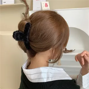 Detailed view of an elegant black plush hair claw clip worn on a model's hair bun