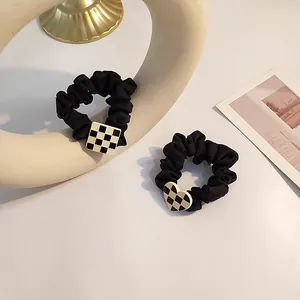 Detail of black satin scrunchies featuring checkered square and heart shape charms