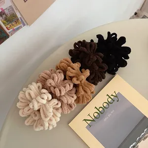 Detail of plush chenille hair scrunchies in five earth tones on a cozy table setting
