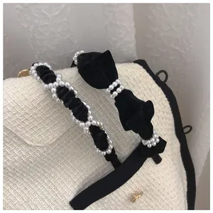 Detailed view of black velvet headbands with pearls and delicate bows on tweed