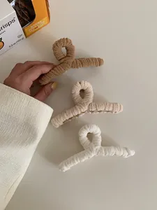 Close-up of three large plush hair claws in coffee, apricot, and creamy white colors