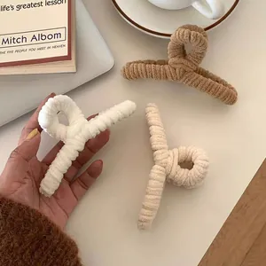 Close-up of large corduroy hair claws in white, beige, and brown with a soft ribbed texture