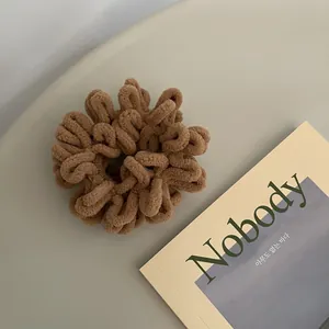 Close-up of thick plush brown scrunchie with soft chenille texture for winter hair styling