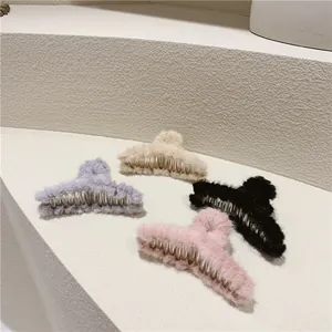 Detail view of large plush hair claws in beige, grey, black and pink set on stone base