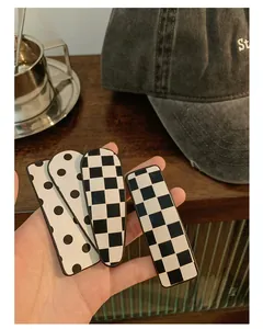 Close-up of four checkerboard and polka dot hair clips with rectangular and teardrop shapes