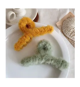 Detail of plush ginger and bean green faux fur hair claws in a white ceramic dish