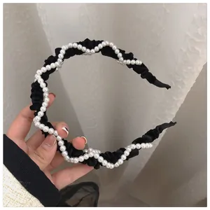Detailed view of black velvet headband with elegant white pearls and pleated texture