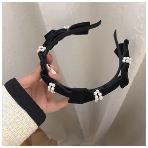 Detail of vintage black velvet headband featuring elegant pearls and bow accents