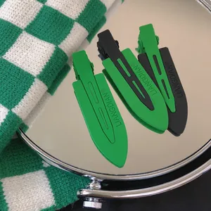 Set of three green and black matte finish hair clips with embossed letters on a round mirror