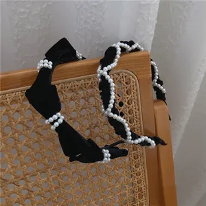 French vintage black velvet headband with elegant pearls and bow design on a rattan chair