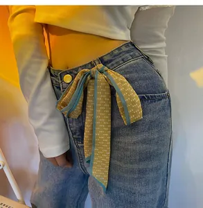 Yellow chiffon scarf with polka dots used as a stylish belt accessory for denim jeans
