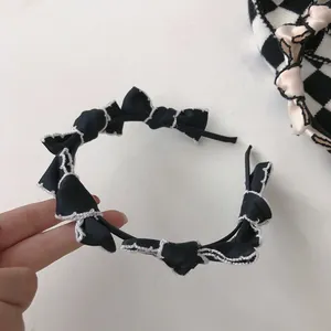 Close-up of black fabric headband featuring multiple bows with white contrast stitching