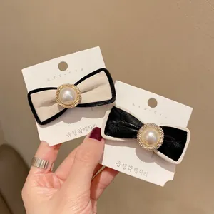 Elegant leather bow hair clips with pearls and gold accents on a display card