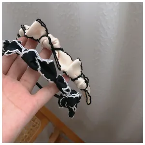 Detail of two French vintage pleated lace headbands in black and cream satin finishes